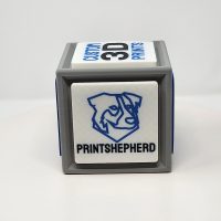 3D printed cube with one side featuring a QR code and the other featuring logos and slogans.